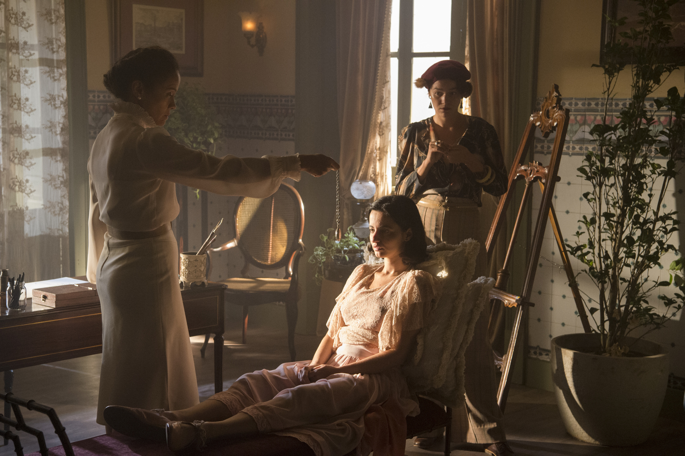 Dra. Selma (Aline Borges) vai começar uma sessão de hipnose com Justina (Julia Stockler). Adelaide (Joana de Verona) está com elas.